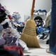 Woman sweeping pathway through piles of laundry